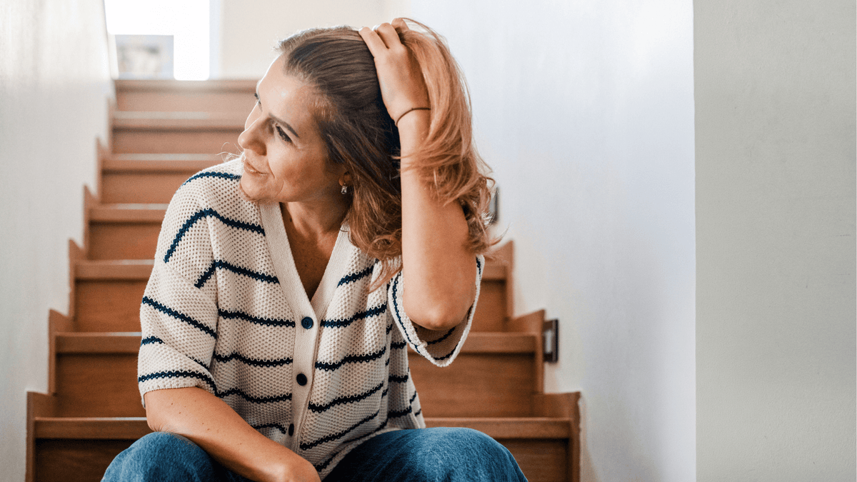 Frau in der Perimenopause sitzt entspannt auf einer Treppe